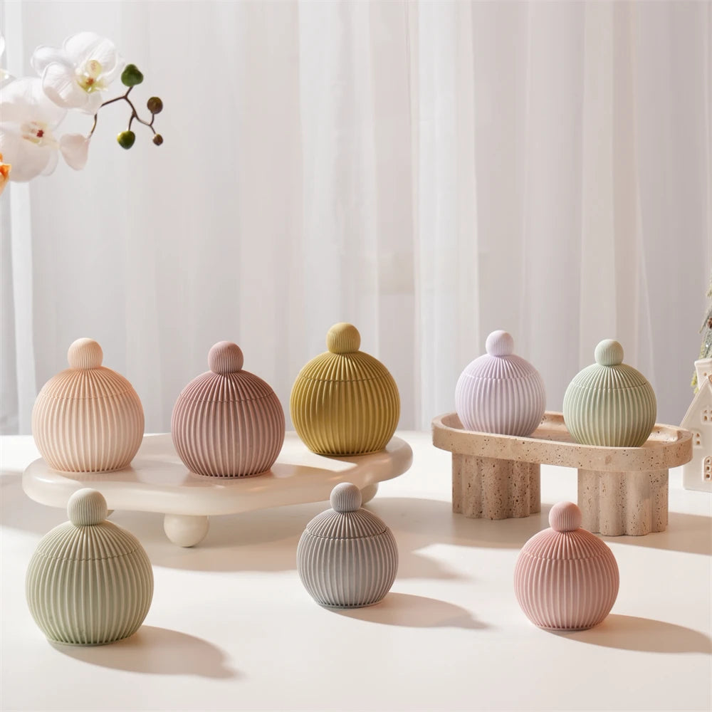 A collection of round silicone candle molds in various muted pastel and natural tones arranged on a white surface.