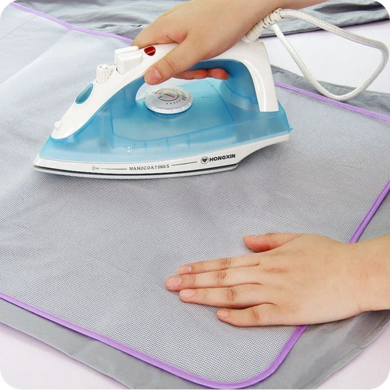 Une main utilise un coussin de protection anti-chaleur bleu et blanc sur un fer à repasser gris.