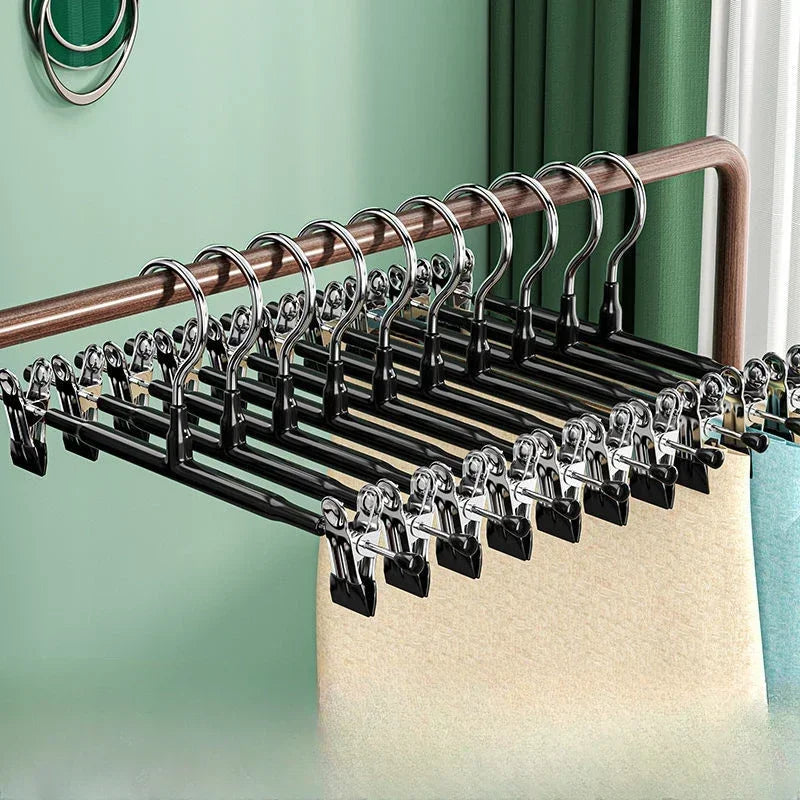 A close-up view of black stainless steel adjustable clothing hangers displayed on a wooden rack.