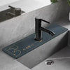 A modern matte black faucet mounted on a dark blue mat in a bathroom sink area.