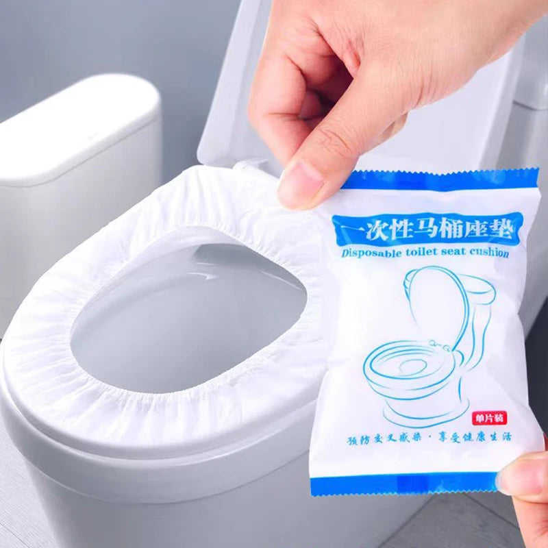A hand is placing a pack of waterproof disposable toilet seat cushion into a white toilet bowl.