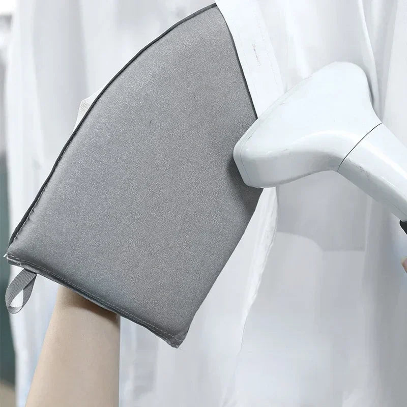 A gray portable ironing board with a handle is shown next to a white garment steamer.