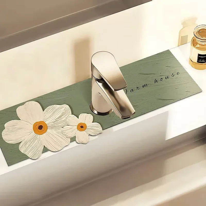 A modern silver faucet mat rests on a green wooden tray next to a small glass jar.