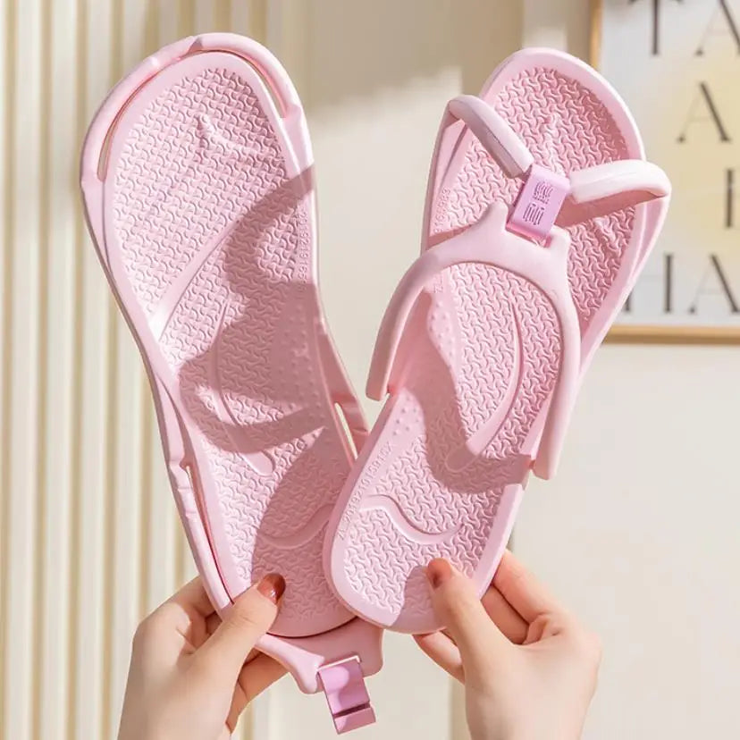 Une paire de tongs pliables en EVA roses tenues par des mains sur un fond clair.