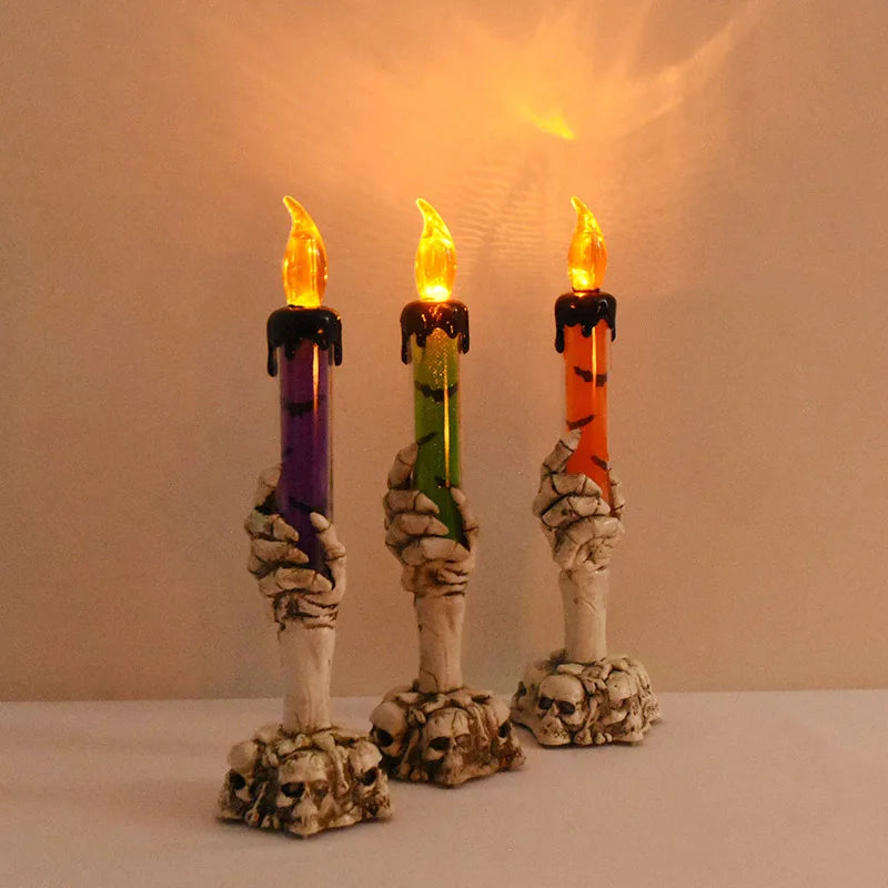Three skeleton hand shaped LED candles with flickering flames on a white surface.