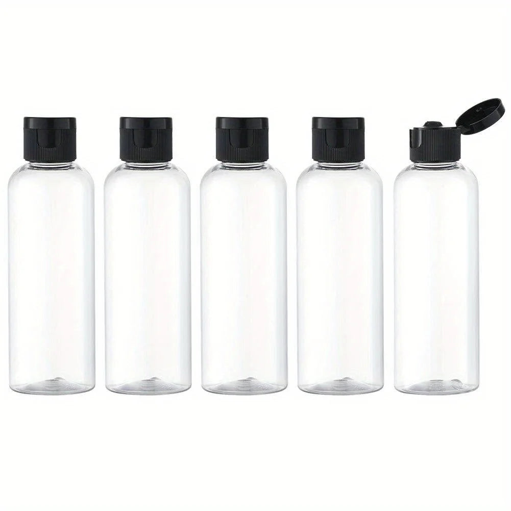 A set of four clear glass refillable travel bottles with black caps and a black pump top.