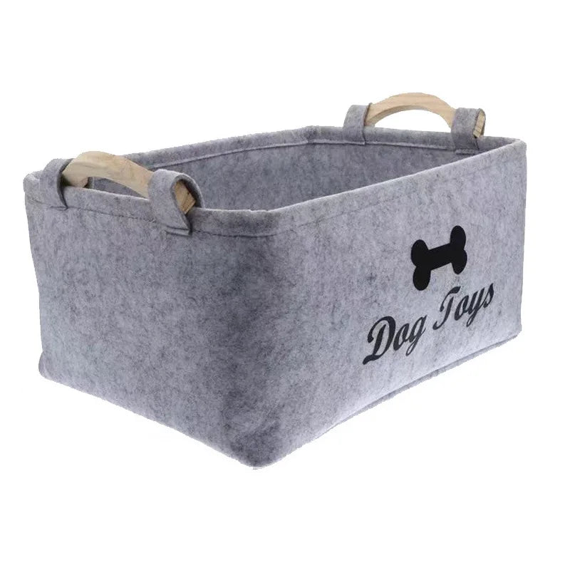 A gray felt storage basket with wooden handles for dog toys.