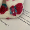 A close-up of a white hair towel headscarf with a vibrant red strawberry print and a pink button detail.