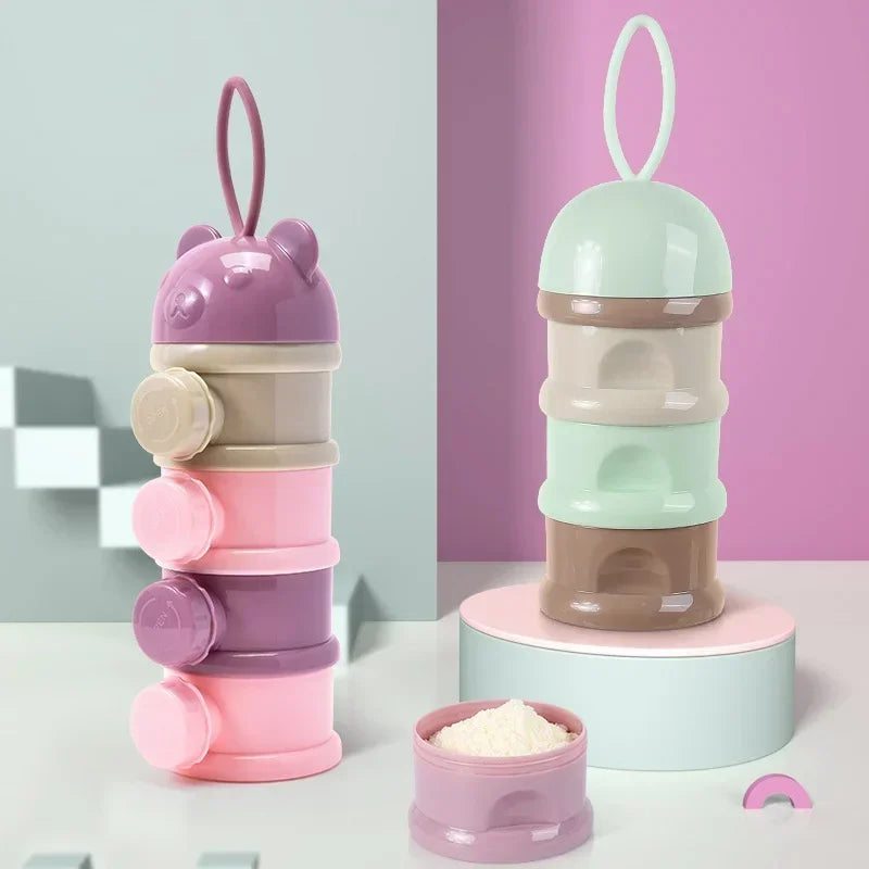 A layered silicone food storage box for baby snacks in shades of purple, pink, and mint green.