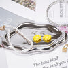 A silver cloud-shaped jewelry organizer tray holding pearl and yellow floral earrings.