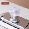 A white flower shaped toilet flush button with a pink center is shown on a chrome fixture.