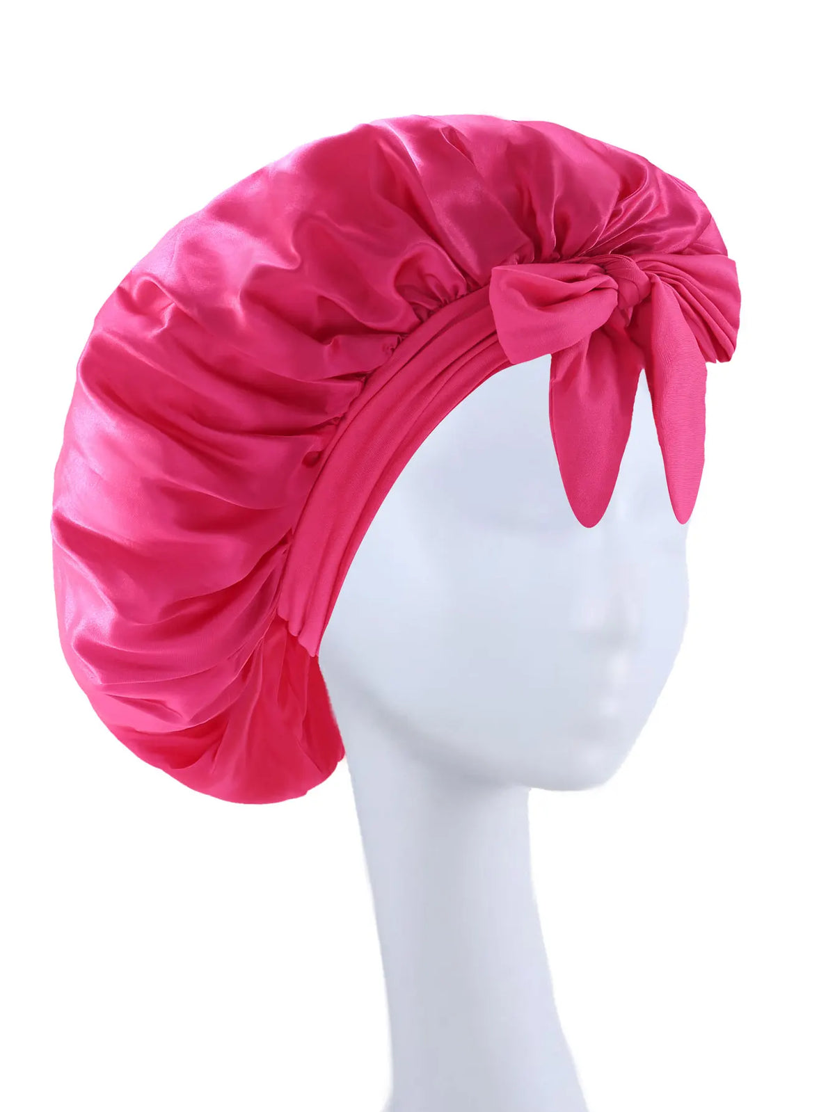 A vibrant pink silky satin sleep bonnet tied with a bow displayed on a white mannequin head.