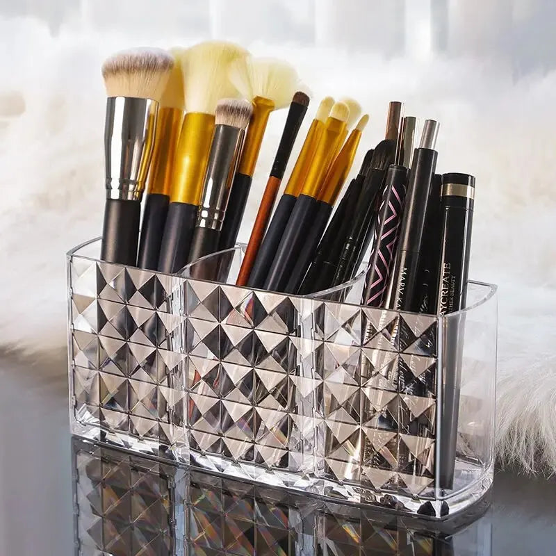 Clear acrylic makeup brush holder with three compartments filled with various makeup brushes