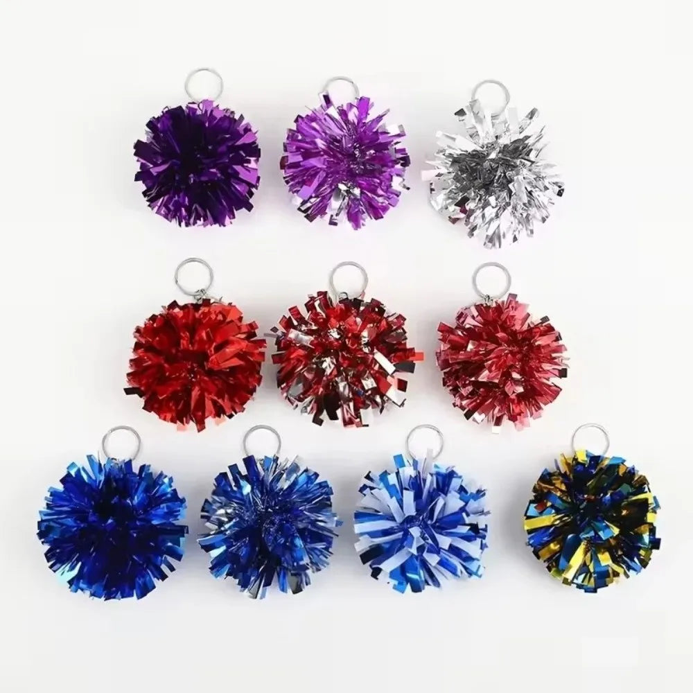 Eine Sammlung farbenfroher Pom-Pom-Anhänger in lila, silber, rot, blau und gelb.