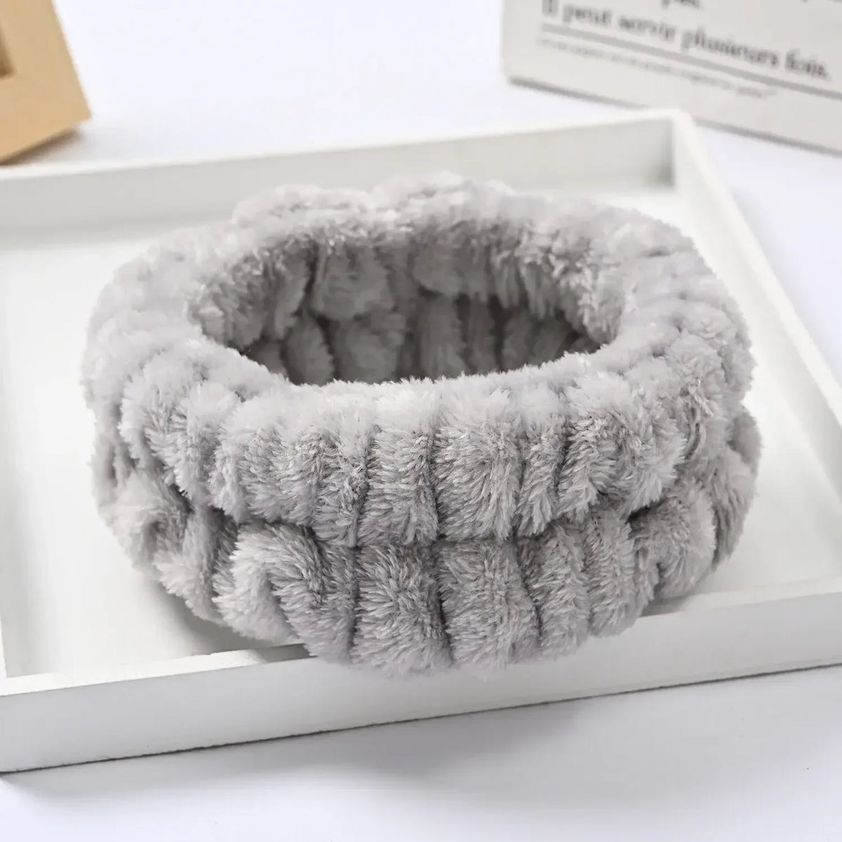 A thick, gray microfiber wrist sweatband set for face washing and skincare is displayed in a white box.