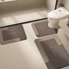 A modern toilet area featuring dark gray floor mats and a white toilet bowl.
