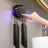 A hand is using a portable UV electric toothbrush cleaner device mounted on a wall above a sink.