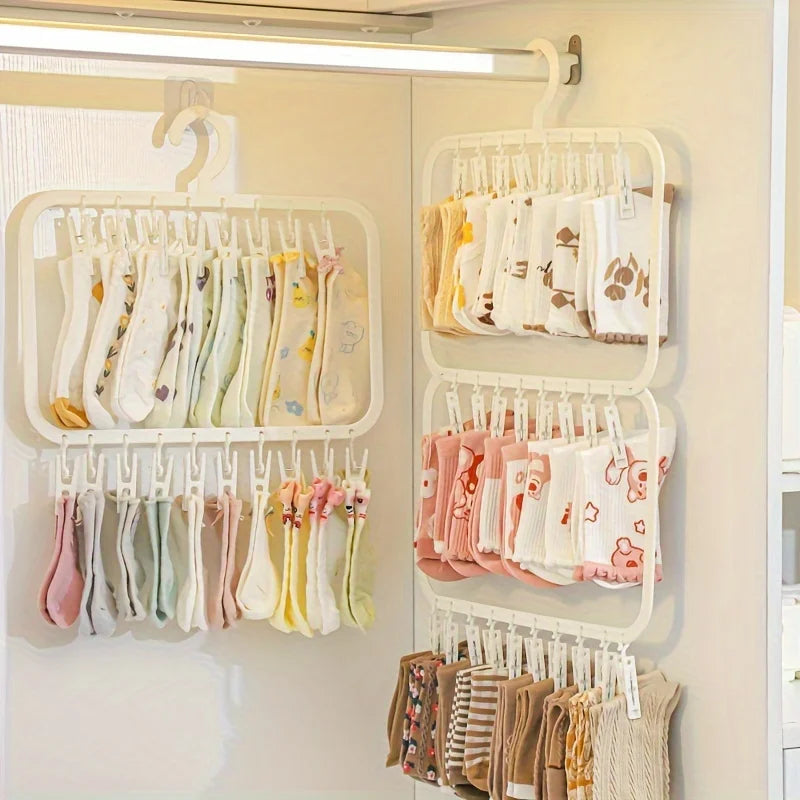 A white multi-clip drying rack displaying various folded white and pastel colored fabric items for laundry and accessories.