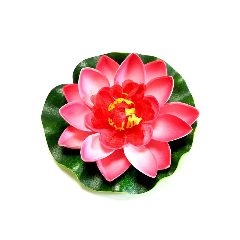 A vibrant artificial lotus flower with pink and red petals and a yellow center, set against green leaves.