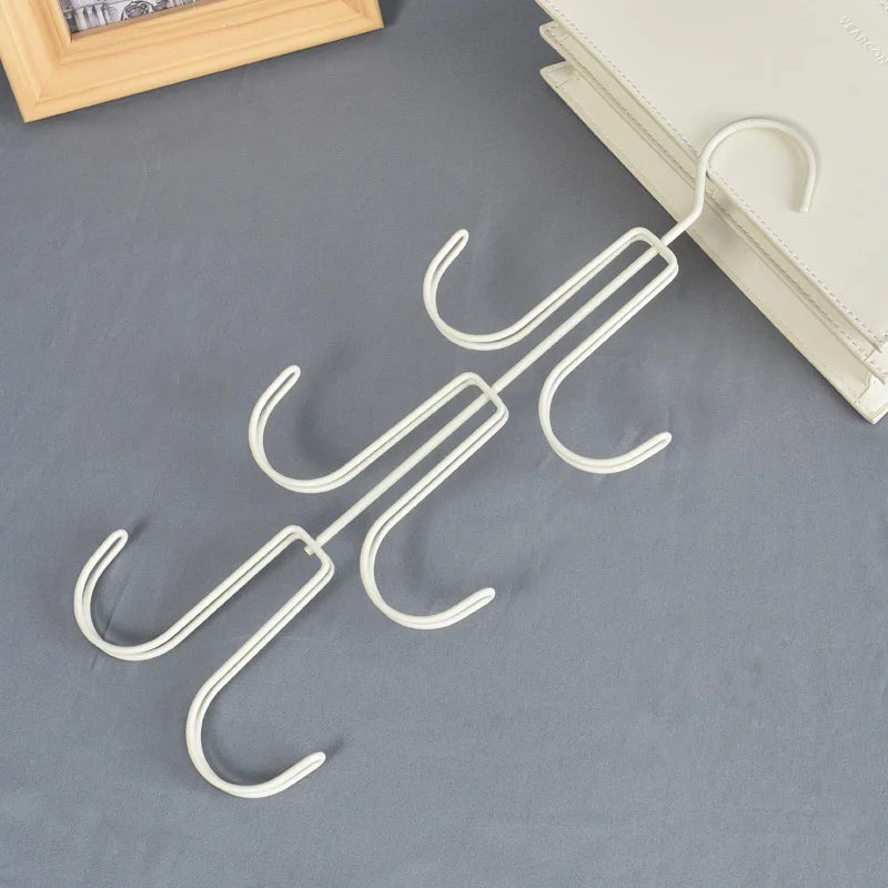 A white multi-layer storage hanger bag organizer displayed on a gray fabric next to a stack of books.