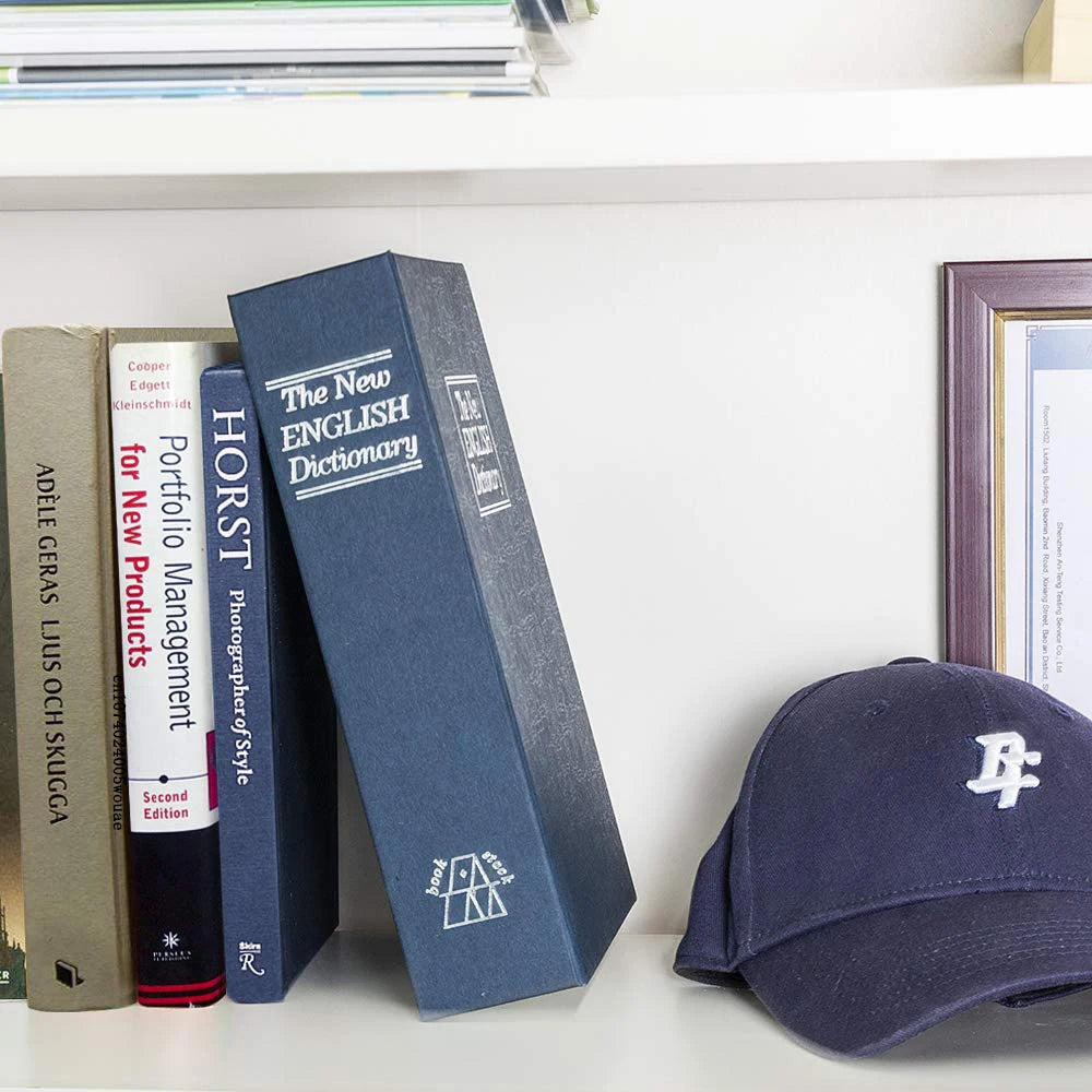 A dark blue hardcover dictionary titled The New English Dictionary sits next to a dark blue cap on a white shelf.