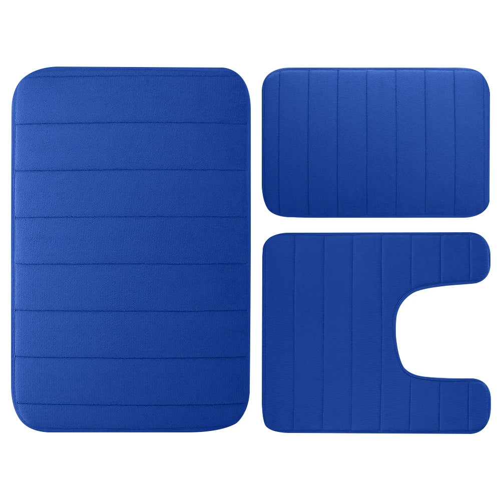 A set of three blue memory foam bathroom rugs, including a rectangular mat and two irregular shapes.