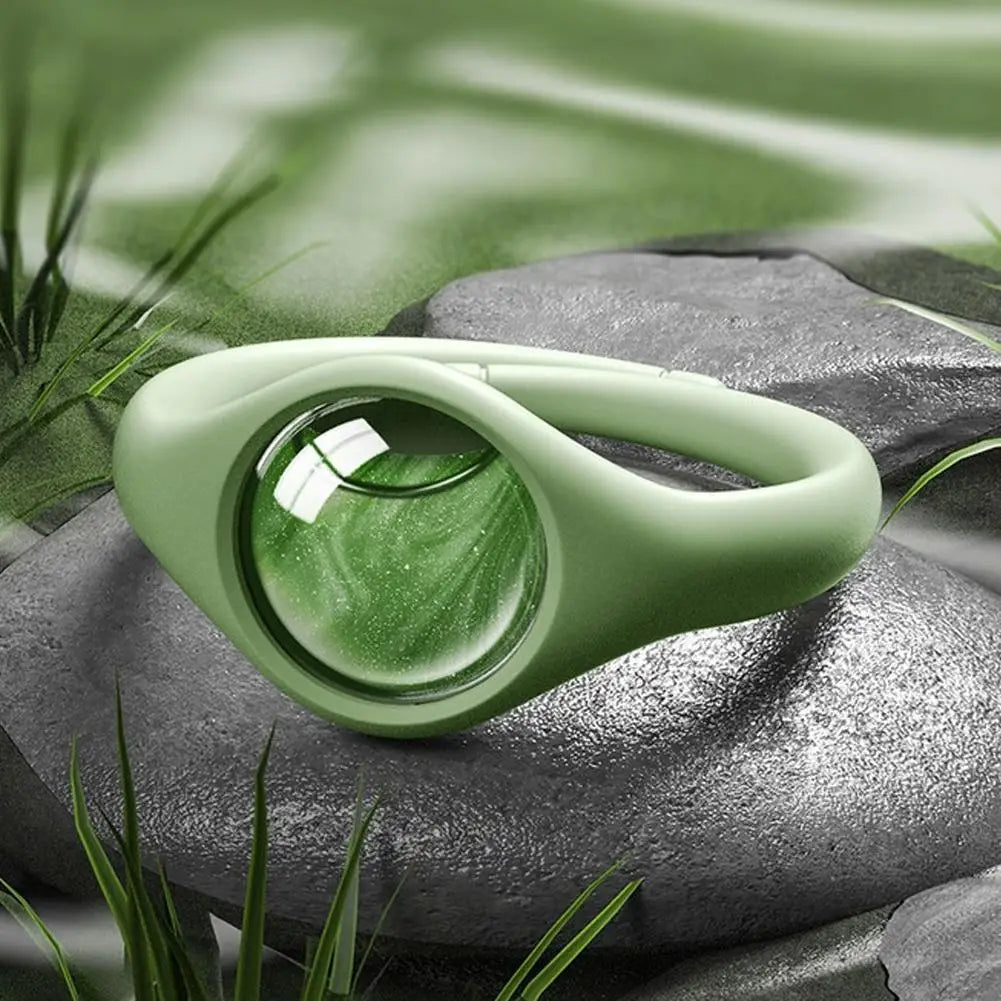 Pulsera repelente de mosquitos verde claro natural sobre piedra gris oscura entre follaje verde.