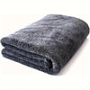 A dark gray microfiber car cleaning towel rolled up on a white surface.