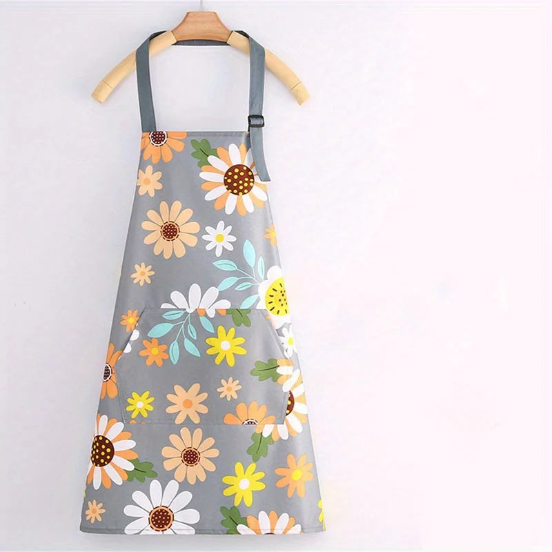 Gray apron with a floral print featuring yellow, orange, and white daisies on a wooden hanger.