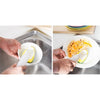 Hands are using a dish wand cleaning brush set to wash food in a stainless steel sink.