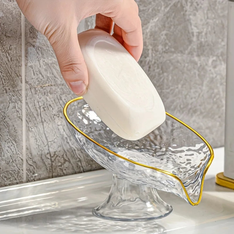 A hand is holding a white oval plastic soap dish with drainage holes over a glass soap dish.