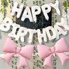 A decorative banner made of white balloons spelling HAPPY BIRTHDAY with pink accents and pink bow decorations.