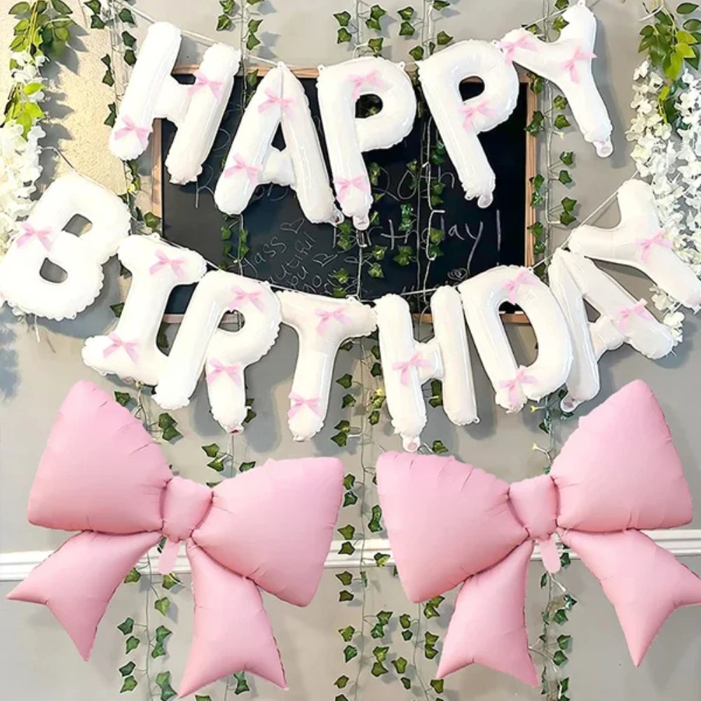 A decorative banner made of white balloons spelling HAPPY BIRTHDAY with pink accents and pink bow decorations.