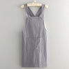 A gray linen cotton kitchen apron hanging on a wooden hanger.