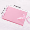 Álbum de scrapbooking rosa personalizable con encuadernación espiral mostrado sobre una superficie de madera blanca.