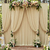 Fondo de tela beige con cortinas fruncidas y follaje floral usado como decoración para bodas o eventos.
