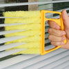A hand holds a yellow cleaning brush with white bristles, used for cleaning window blinds.