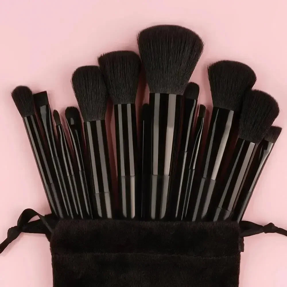 A set of black luxury vegan makeup brushes bundled together on a pink background.