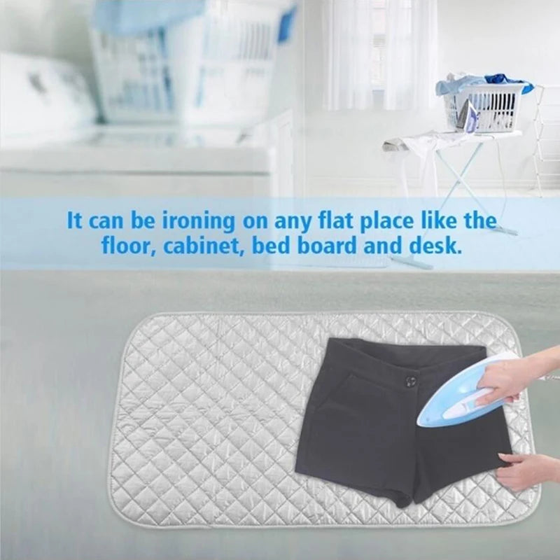 A person ironing a black garment on a quilted mat on a flat surface like the floor or desk.