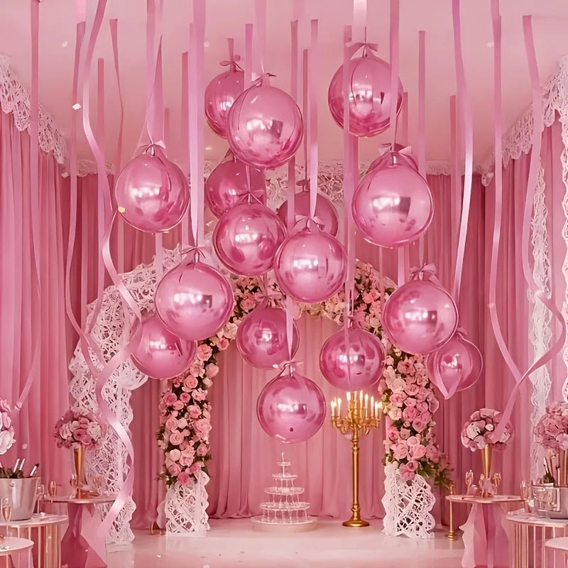 Exhibición de globos metálicos rosados en varios tamaños colgando contra un fondo de tela rosa y arreglos florales.
