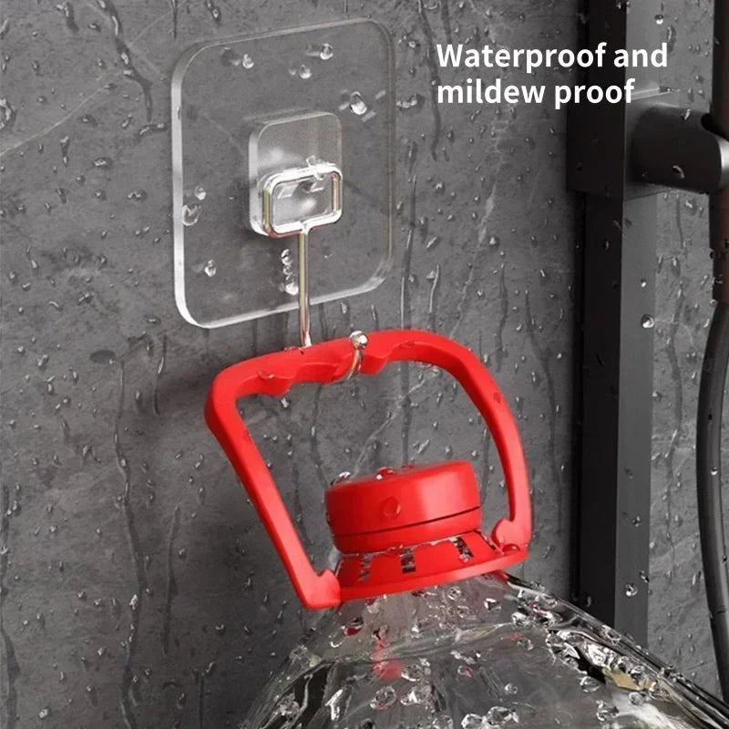 A red rotating wall hook is attached to a clear adhesive plate on a dark gray textured wall.