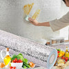A hand applies a self-adhesive aluminum foil kitchen wall sticker to a textured wall, with the rolled foil and related ingred