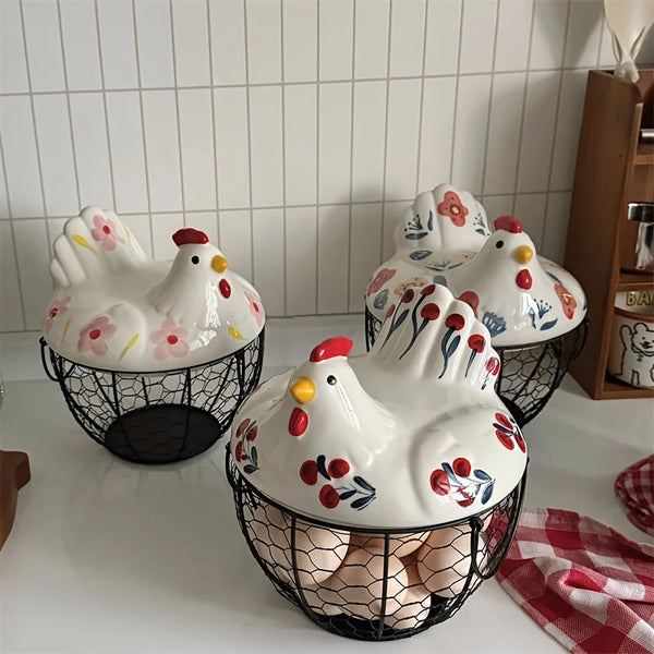 A rustic ceramic hen-shaped fruit basket with white and pink painted hens sitting on a white surface.
