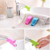 Flexible silicone faucet extenders in pink, blue, and green colors used for easy washing.