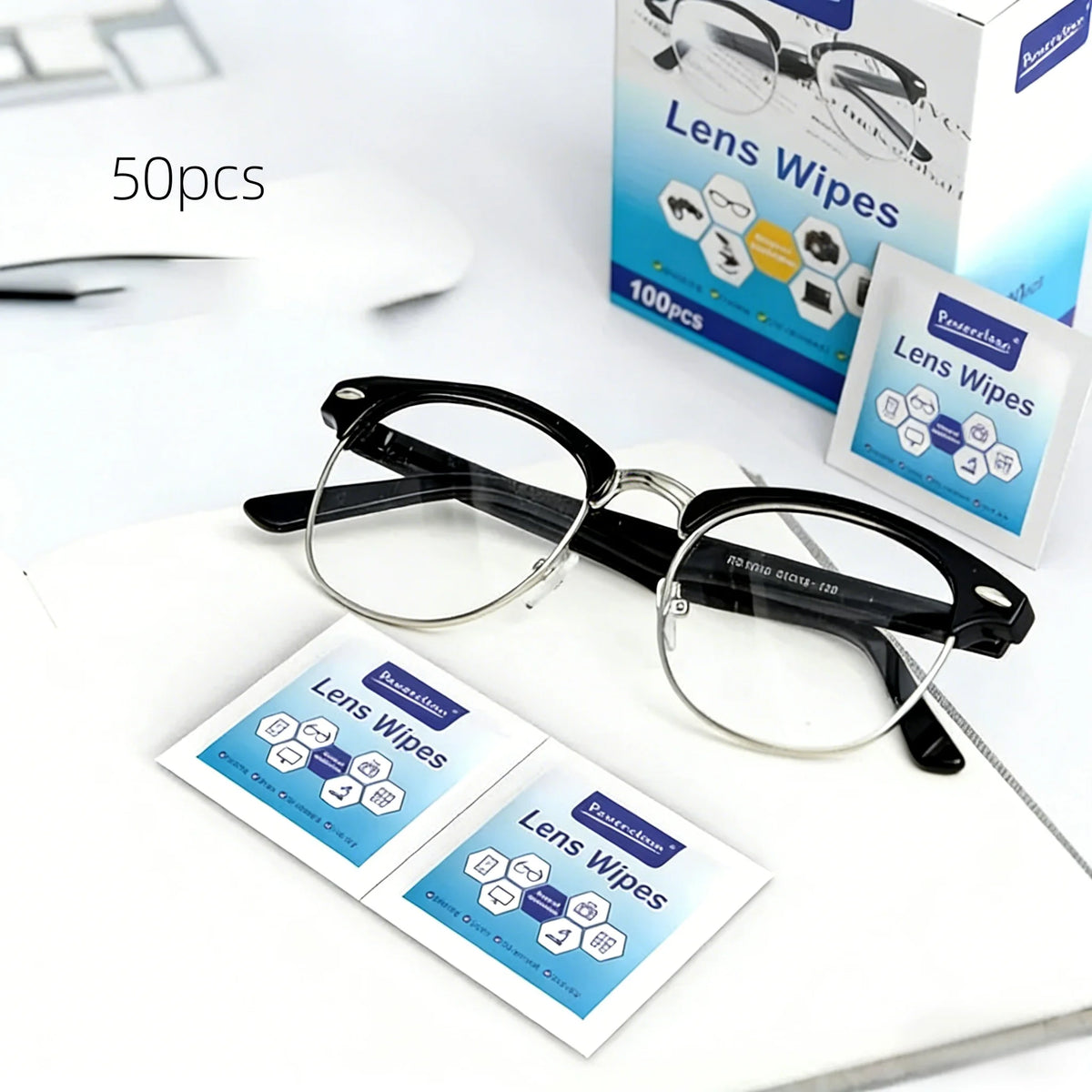 A set of lens wipes is shown next to a pair of eyeglasses and a box for cleaning glasses and screens.