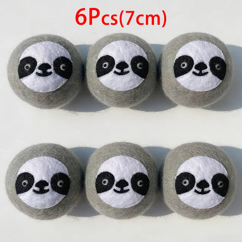 Six grey wool dryer balls shaped like pandas with black eyes and nose.