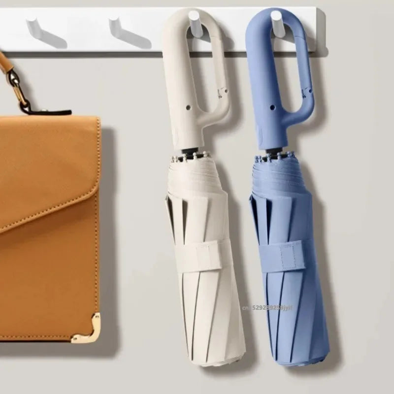 A pair of automatic folding umbrellas, one white and one blue, are displayed hanging on a wall mount.