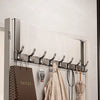 A silver over-the-door organizer rack with extended arms mounted on a white wall, featuring hooks for hanging items.