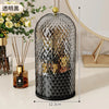 A black glass organizer for makeup brushes with a gold lid and decorative geometric pattern.