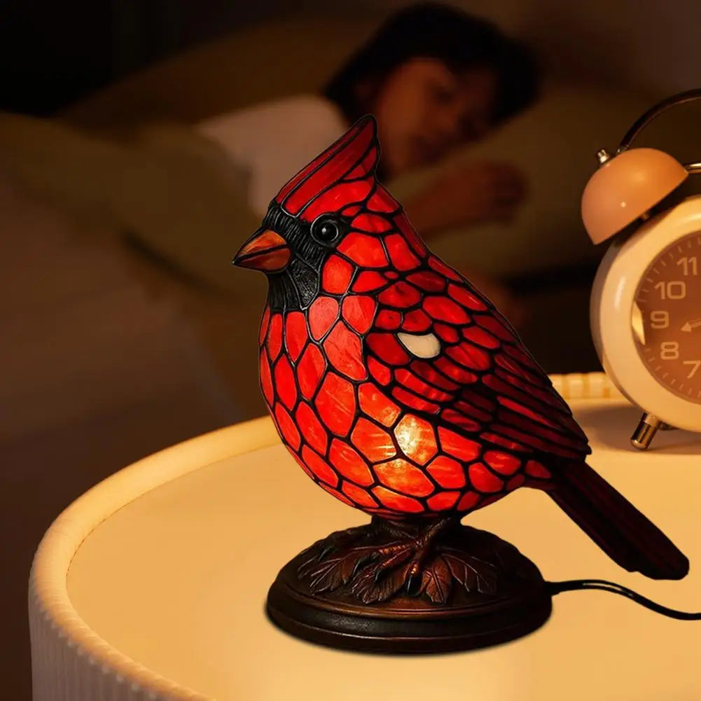 A decorative resin bird table lamp shaped like a red and black bird sitting on a wooden base.